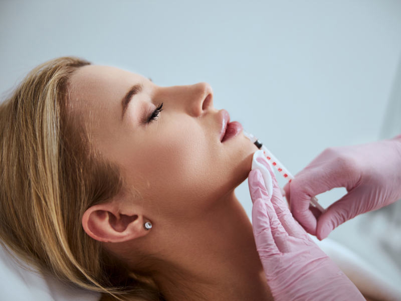 A woman receives a chin filler injection for facial contouring