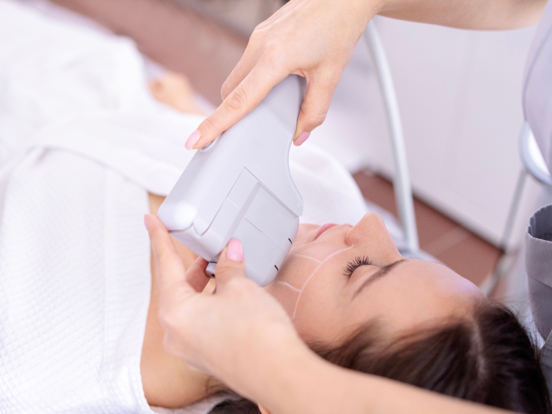 Aesthetician using HIFU device for non-invasive face contouring treatment