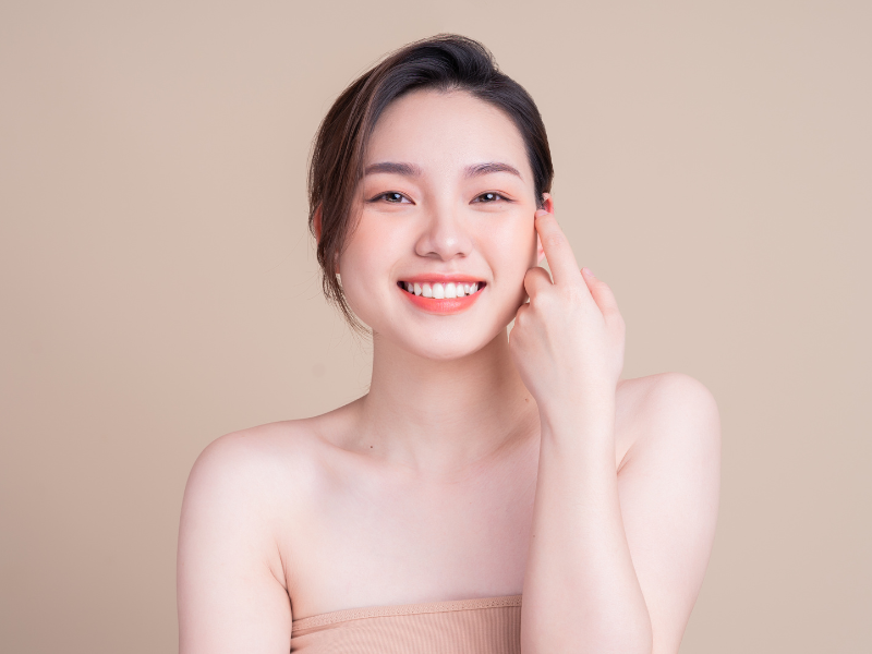 Smiling woman touching her face with glowing, healthy skin