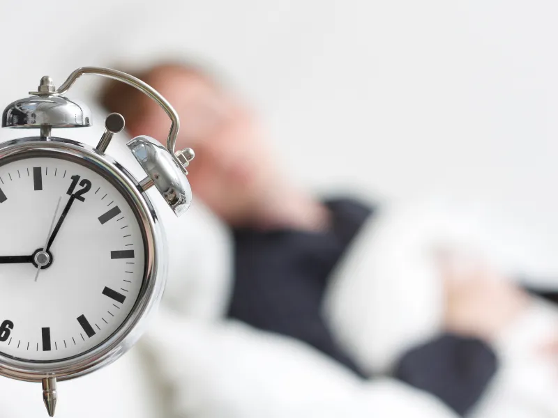 Alarm clock with blurred person sleeping in the background for rest