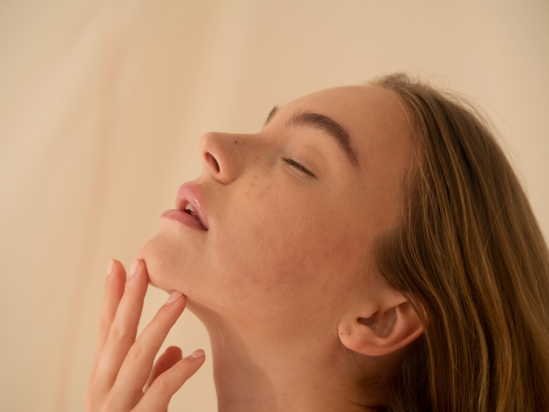 Woman gently touching chin with smooth and radiant skin
