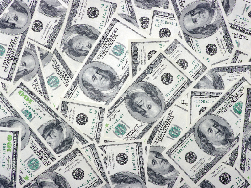 Hundred-dollar bills arranged in an overlapping pattern on table