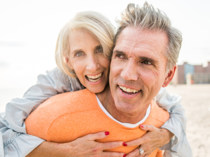 Happy elderly couple embraces while smiling on a sunny beach