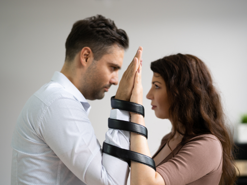 A couple with hands tied together, staring at each other