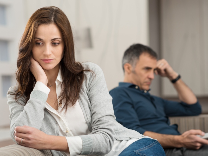 A woman and man sitting apart, looking sad and distant