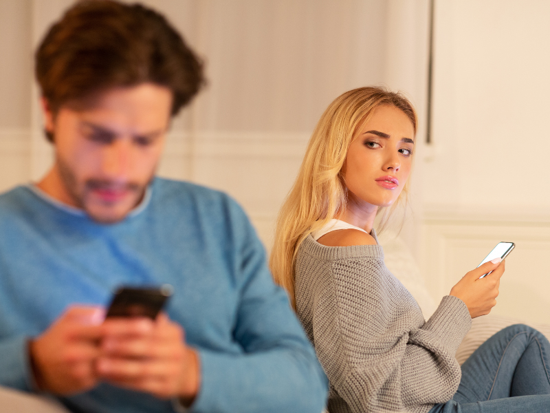 A woman glancing at her partner glued to his phone