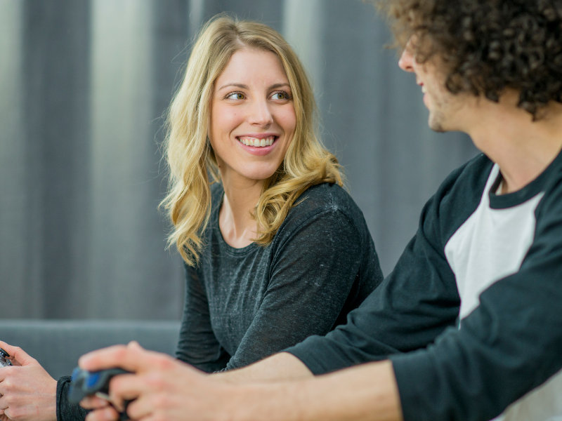Woman smiles while playing video games with male friend
