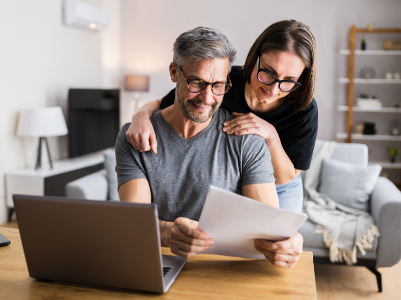 A smiling couple reviewing documents together in a home office