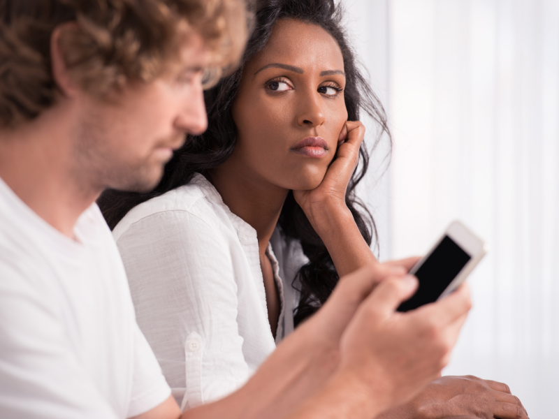 A woman looking annoyed as her partner focuses on phone