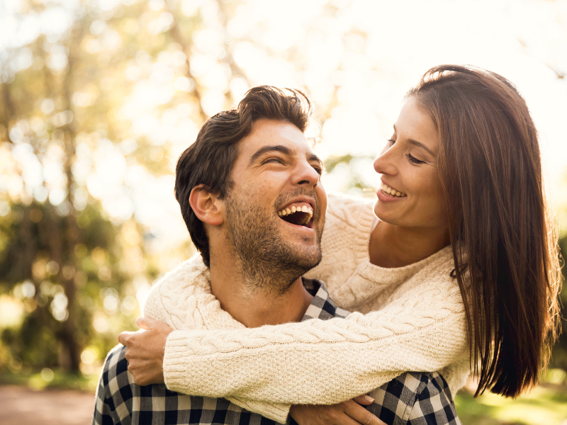 A couple laughing while embracing in a warm outdoor setting
