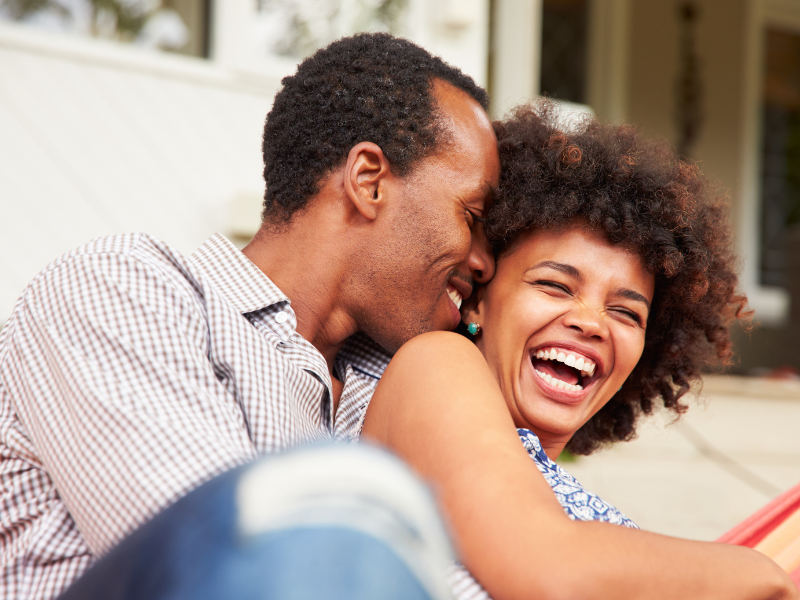 A couple happily laughing together while sitting outside their home