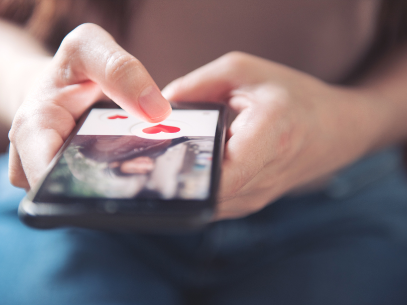 Person swipes right on dating app with heart icon
