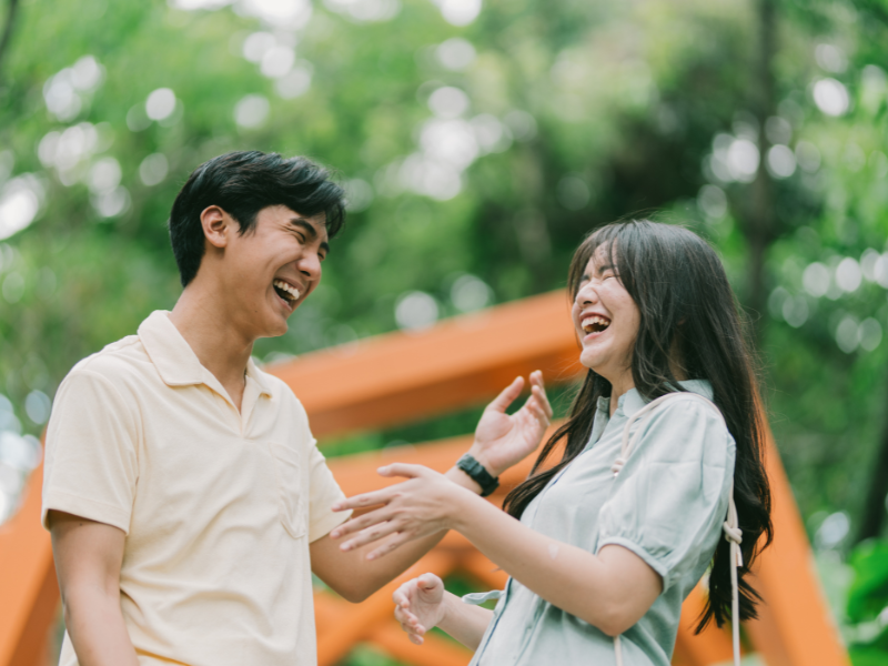A young couple laughing and joking in a green park