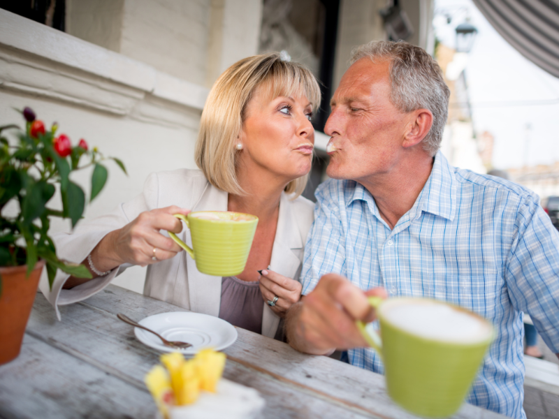 Older couple drinks coffee and shares playful moment outside