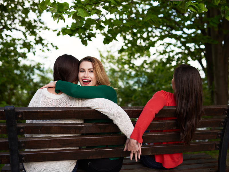 A woman smiling while secretly holding hands with another person