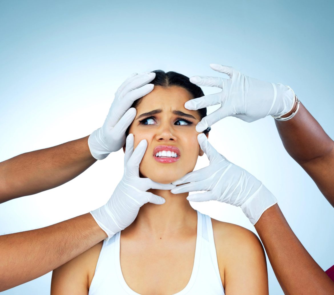 girl with two pairs of hands with gloves touching her face