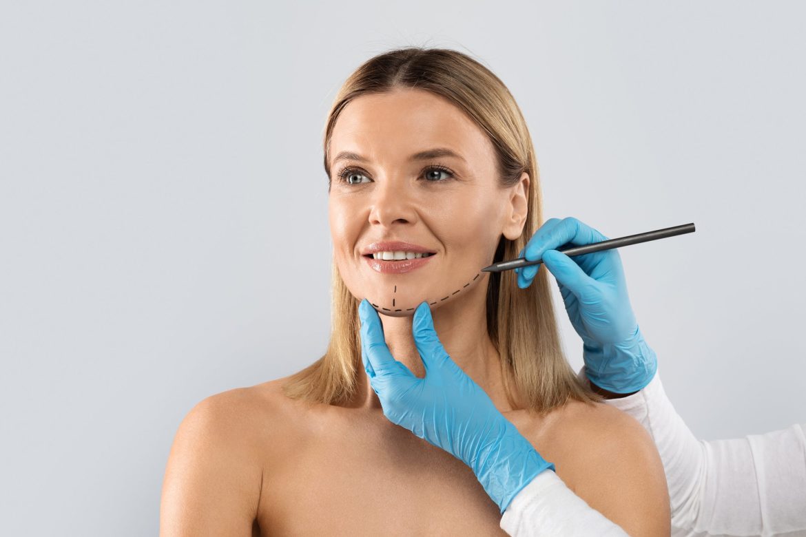 plastic surgeon drawing contours on a female patient's jaw