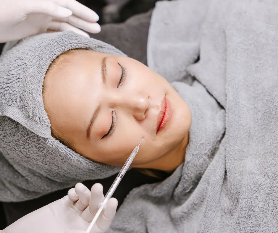 A woman receiving a cosmetic injection while lying on a treatment bed