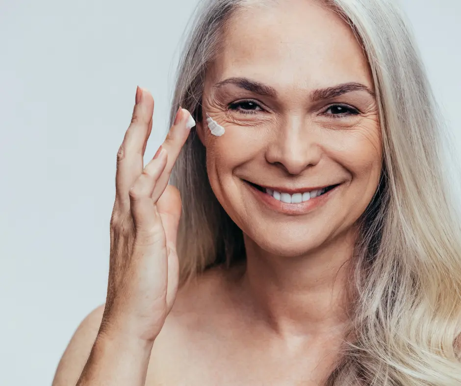 Older woman applying anti-aging cream with a happy smile