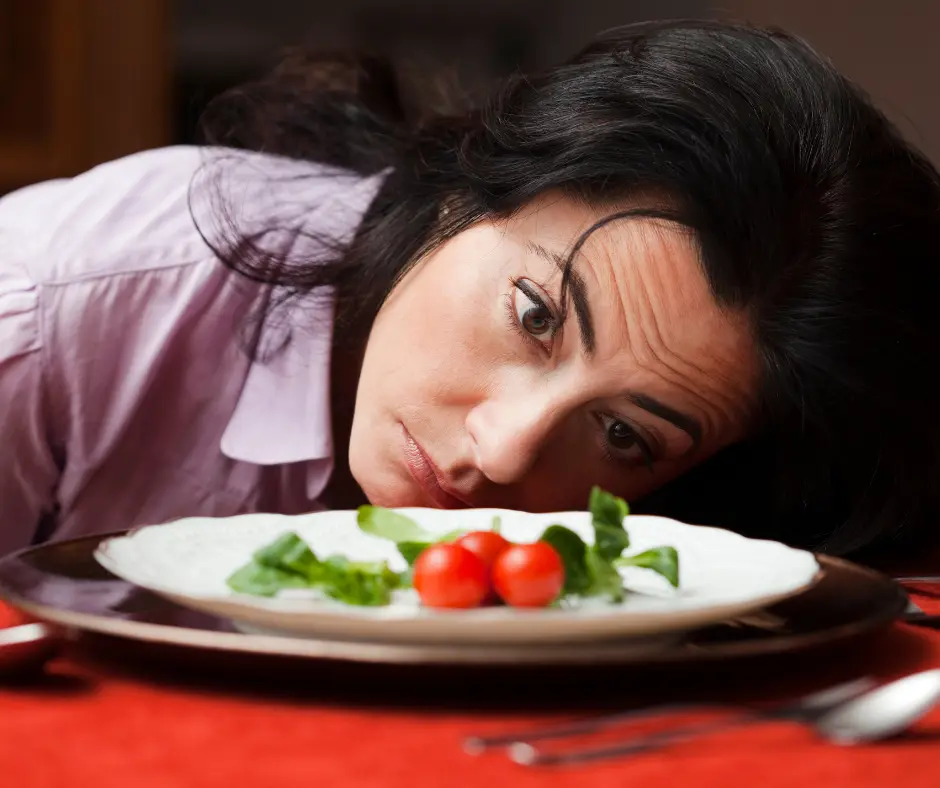 Woman looking frustrated at small salad on dinner plate