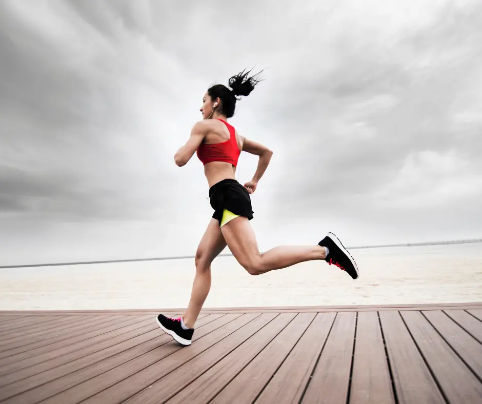 A fit woman running on a wooden boardwalk with a cloudy sky