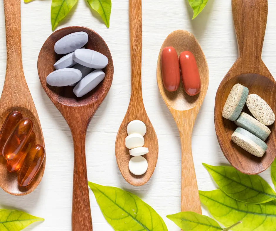 Wooden spoons filled with different supplement pills and capsules