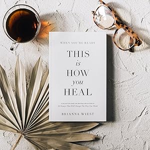 When You're Ready, This Is How You Heal Book on a marble table with glasses, dry leaf and a cup of warm tea