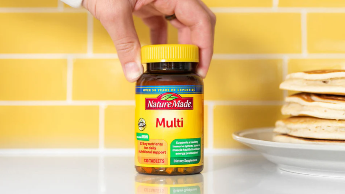 nature made bottle being held on top of a white table and yellow brick wall