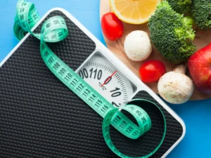 Scale with measuring tape surrounded by fresh fruits and vegetables