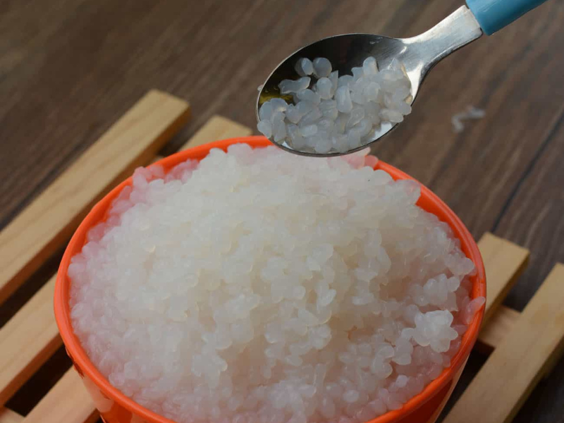 Soft, translucent shirataki rice in an orange bowl with spoon