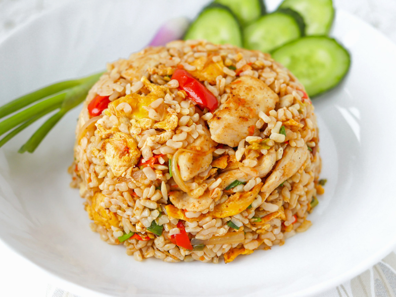 A plate of spicy fried rice with chicken and vegetables