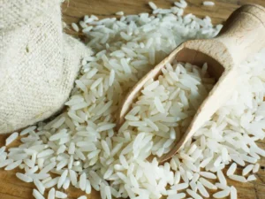 A wooden scoop filled with uncooked white rice on burlap