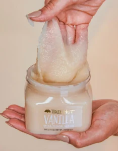 Tree Hut Vanilla Shea Sugar Scrub product being scooped by a hand out of the tub