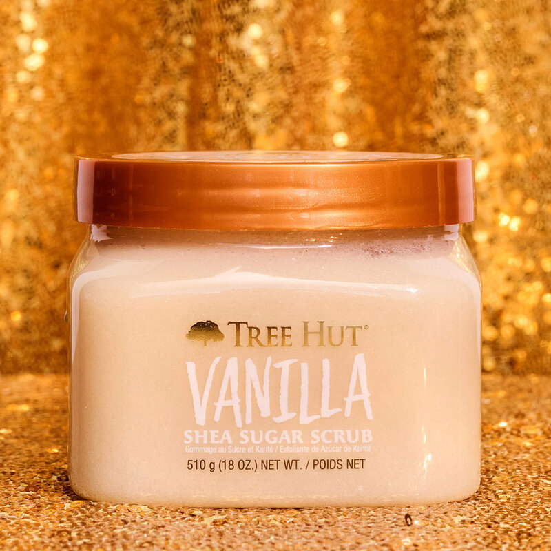 a tub of Tree Hut Vanilla Shea Sugar Scrub in front of a glitter gold background