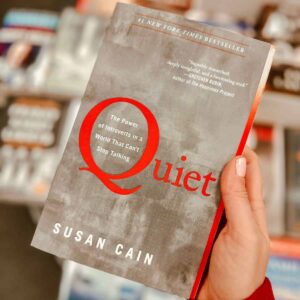 Quiet Book held by a hand in front of a bookshelf